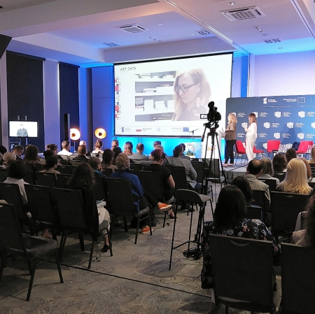 View of the stage, people sitting on chairs in front of it
