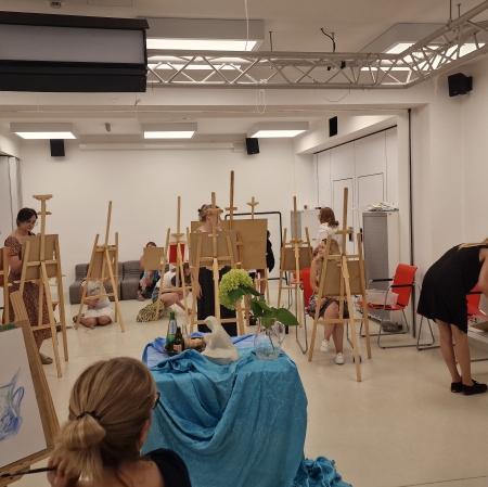 kilkanaście osób w sali warsztatowej stojących przy sztalugach