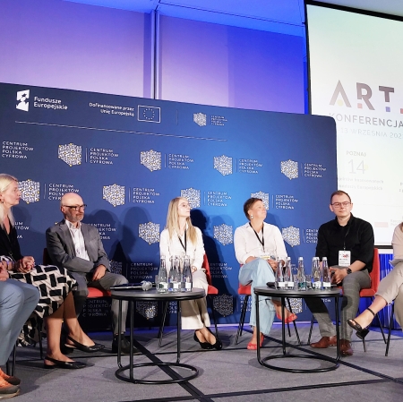 7 people sitting in a semi-circle on chairs on the stage