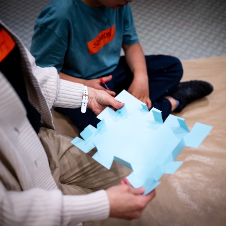 Hands holding a shape cut out from blue paper