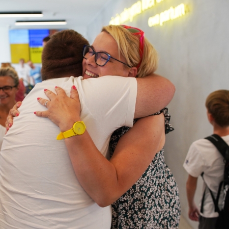 Two people embracing, another person in the background