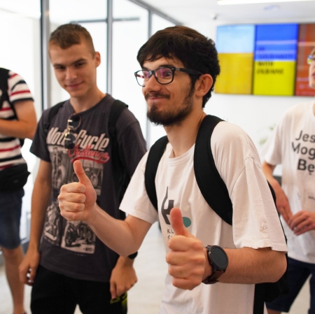 Person showing thumbs up, other people in the background