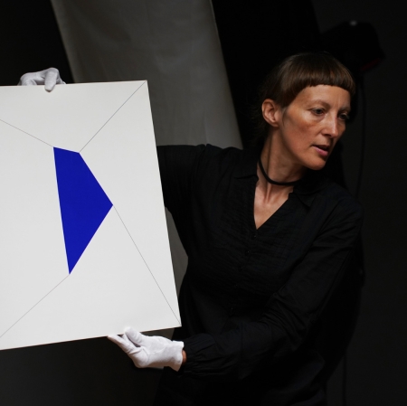 person in white gloves showing a painting