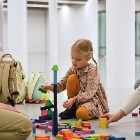 A girl sitting on the floor and stacking wooden blocks