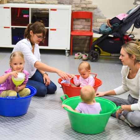 girls sitting in colorful bowls, taking part in sensory activities, playing with various substances