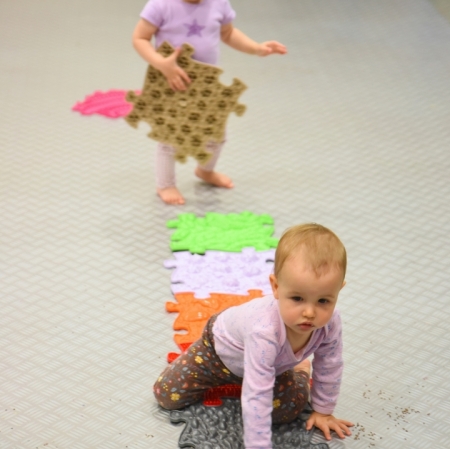 a girl crawling on a path consisting of mats with various structures