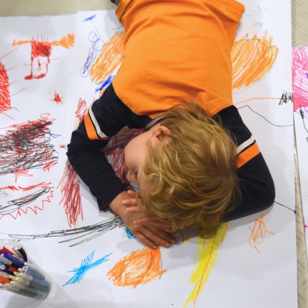 a boy lying on his stomach on a work he painted