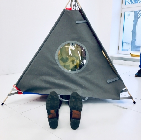 A triangular tent with legs sticking out of it