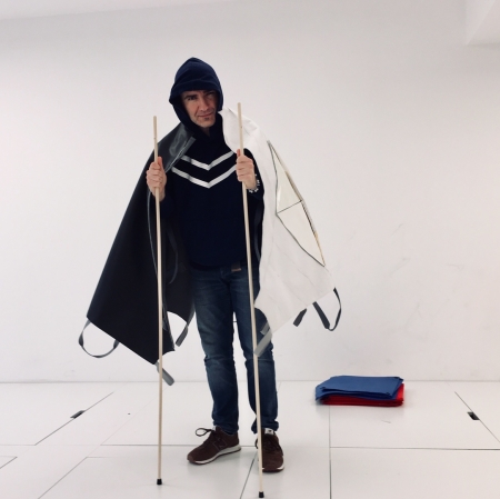 A standing person has a cape over his shoulders