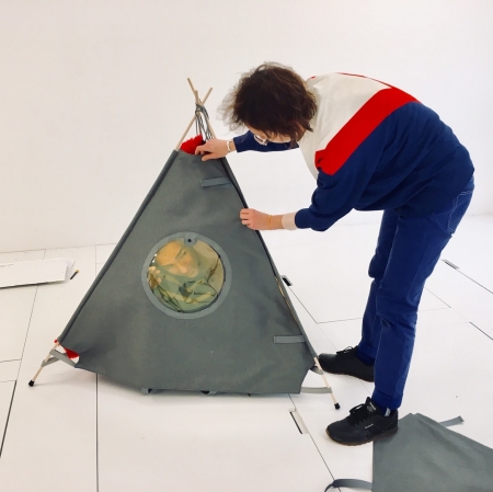 A person leaning over a small triangular tent