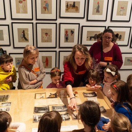 Exhibition space. Several children with their guardians are standing near the display case.