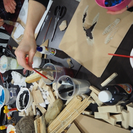 visible hands of people sitting at the table; cardboard boxes and plastic cups on the table