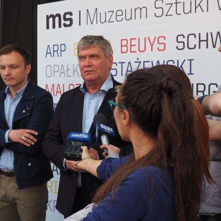 People standing in front of microphones, other people around