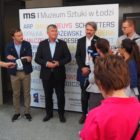 People standing in front of microphones, other people around