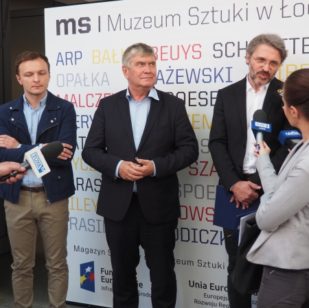 People standing in front of microphones, other people around