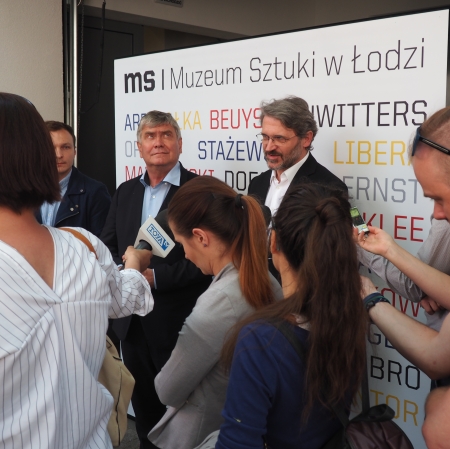 People standing in front of microphones, other people around