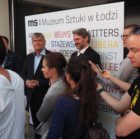 People standing in front of microphones, other people around