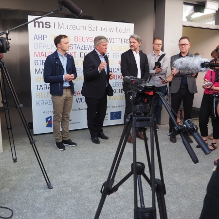 People standing in front of microphones, other people around