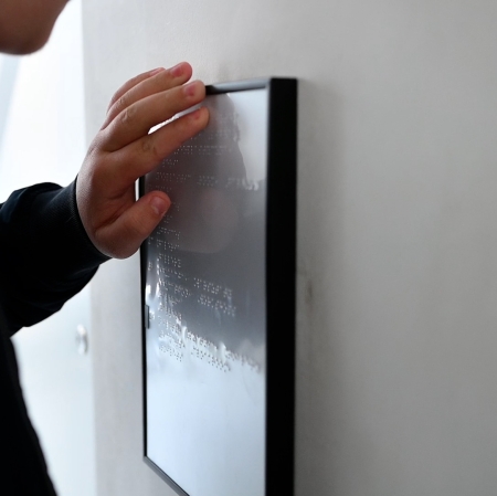 Hand touching a tablet with text in Braille