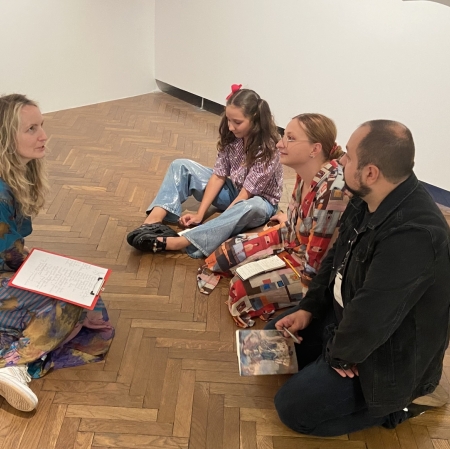 a group of people sitting on the ground and writing something down in notebooks