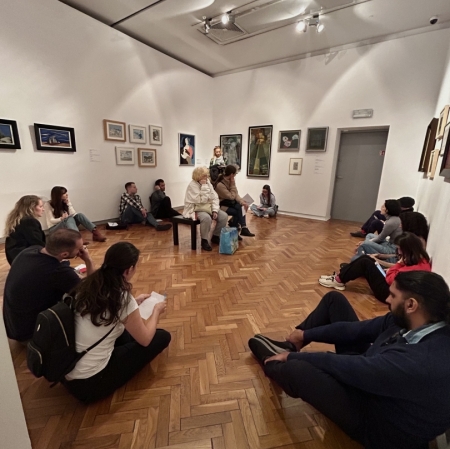 a dozen or so people are sitting on the floor in the exhibition space