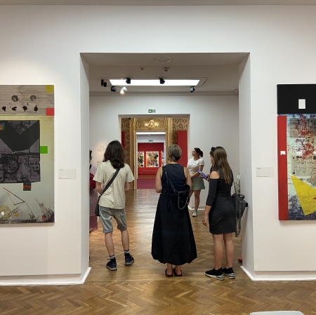 trzy osoby w portalu, po obu stronach na ścianach wiszą obrazy