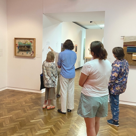 kilka osób w przestrzeni wystawy, widocznych tyłem