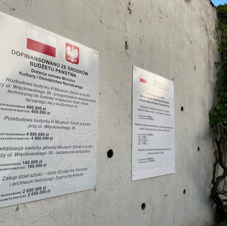 Zdjęcie tablic informacyjnych wiszących na szarym murze