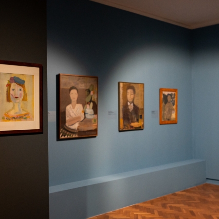 Widok wystawy. Widzimy dwie ściany łączące się w rogu, na których wiszą obrazy. 