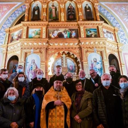 Zdjęcie w cerkwi po panichidzie w intencji Katarzyny Kobro. Osoby w dwóch rzędach, w maseczkach na twarzy i ubraniach zimowych stoją na tle bogato zdobionego ołtarza. fot HaWa