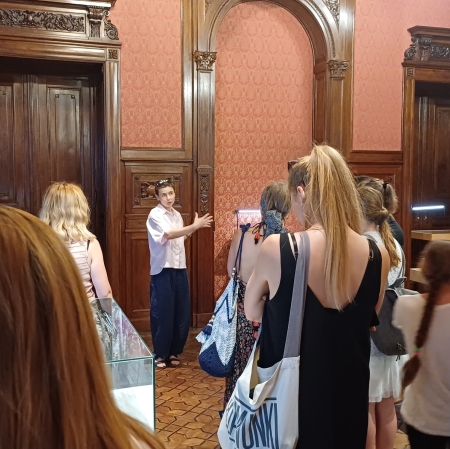 grupa osób w przestrzeni wystawy Zygmunt Krauze. Archiwum Twórcze, słuchające edukatorki prowadzącej oprowadzanie