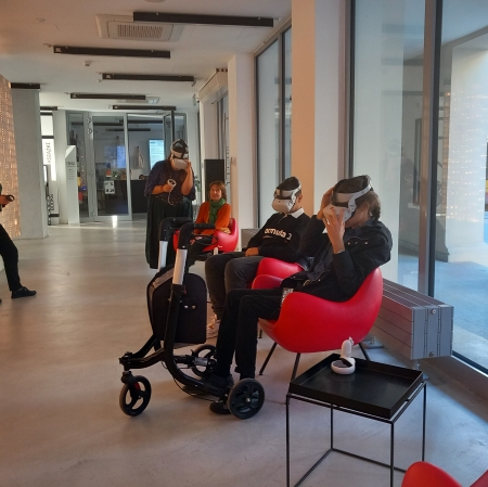 osób siedząca na czerwonych fotelach i koszystająca z googli VR