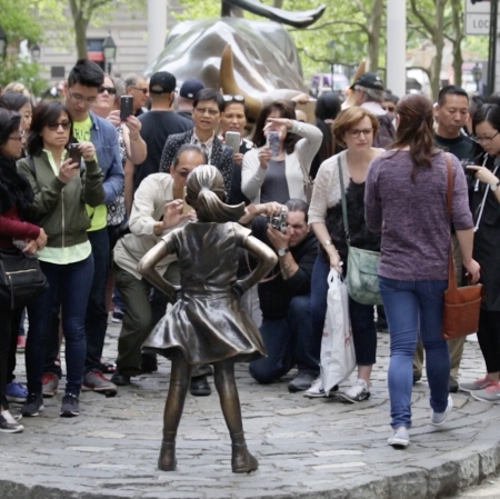 Gathered people at the sculpture of a girl on Wall Street
