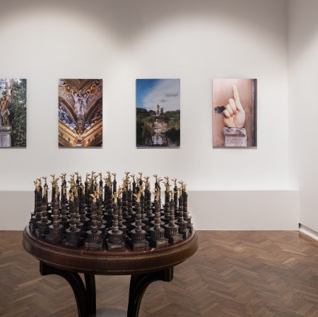 Exhibition space. In the middle of the table with miniatures of the monument. In the background, paintings hung on the wall,