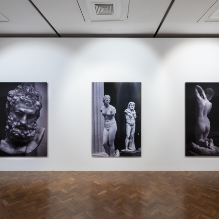 Exhibition space. Three paintings hanging on the wall.