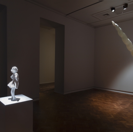 unicorn horn protruding from the wall, on the other side a statue of a little girl. 