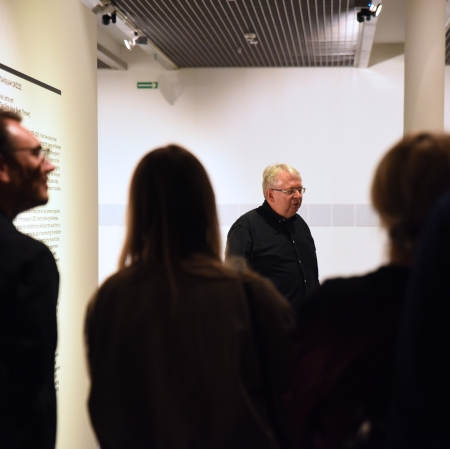 Grupa osób w przestrzeni wystawy podczas oprowadzania kuratorskie Pawła Polita