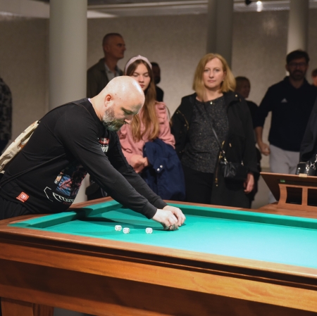 Grupa osób grająca w kości w przestrzeni wystawy.