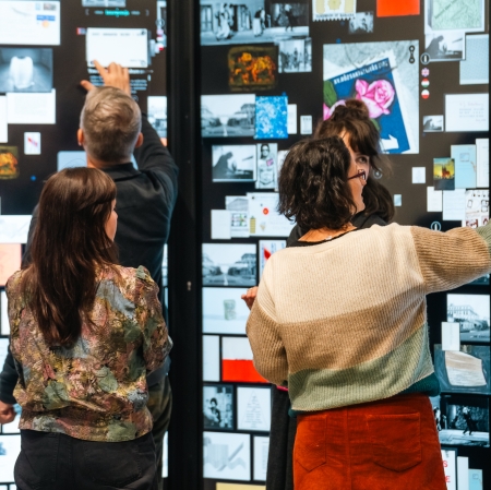 kilka osób stoi przed ekranami, na których wyświetlane są zdjęcia. 