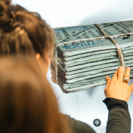 widok od tyłu na dziewczynę, ktora dotyka grafikę, na której przedstawiona jest gazeta.