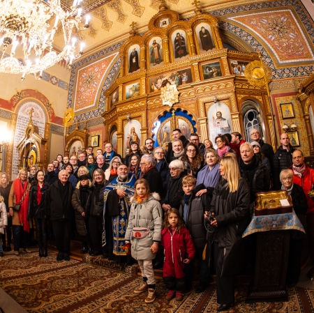 Zdjęcie w cerkwi po panichidzie w intencji Katarzyny Kobro. Osoby w kilku rzędach i ubraniach zimowych stoją na tle bogato zdobionego ołtarza.