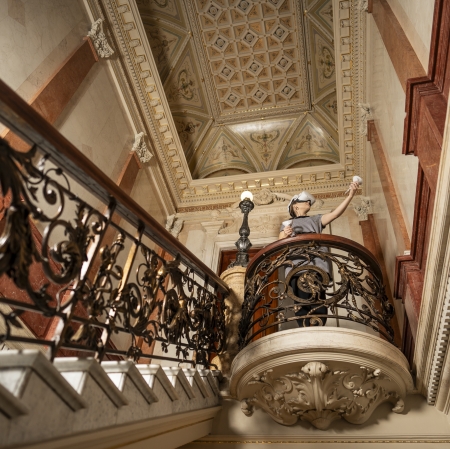 osoba w googlach vr stojąca na szczycie starodawnych schodów obłożonych jasnym marmurem, wykończonych ozdobną balustradą