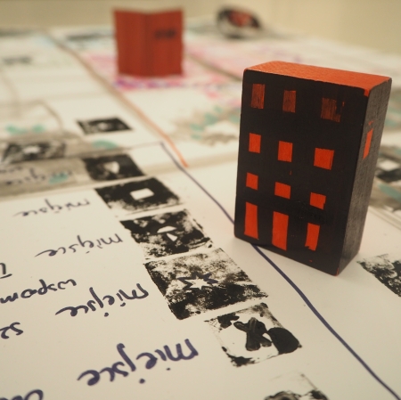 klocek pomalowany na kształt bloku mieszkalnego, ustawiony na naszkicowanej mapie