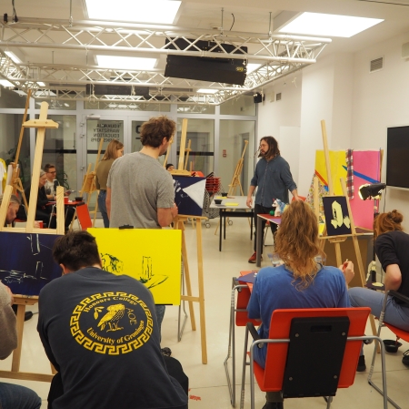 Grupa osób siedząca przy sztalugach i malująca obrazy