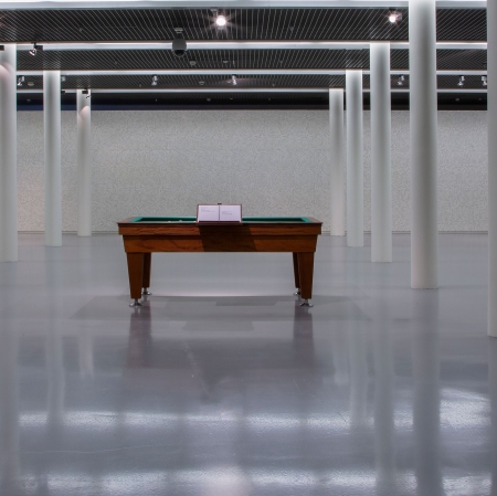 Widok wystawy, na środku stół do gry, po bokach rzędy filarów, wokół ściany pełne kości.