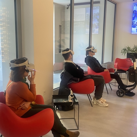 osób siedząca na czerwonych fotelach i koszystająca z googli VR