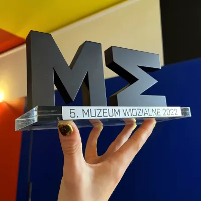 Statuette of the Visible Museum Award, in the background the Neoplastic Room